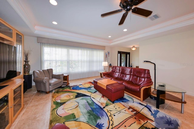 living room with light tile patterned flooring, ceiling fan, crown molding, and a raised ceiling