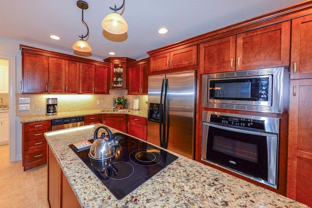 kitchen featuring appliances with stainless steel finishes, pendant lighting, decorative backsplash, light tile patterned floors, and light stone countertops