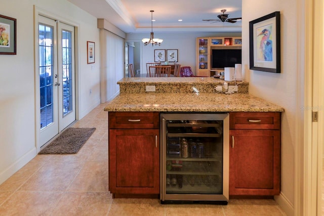 kitchen with decorative light fixtures, wine cooler, a tray ceiling, light stone countertops, and french doors