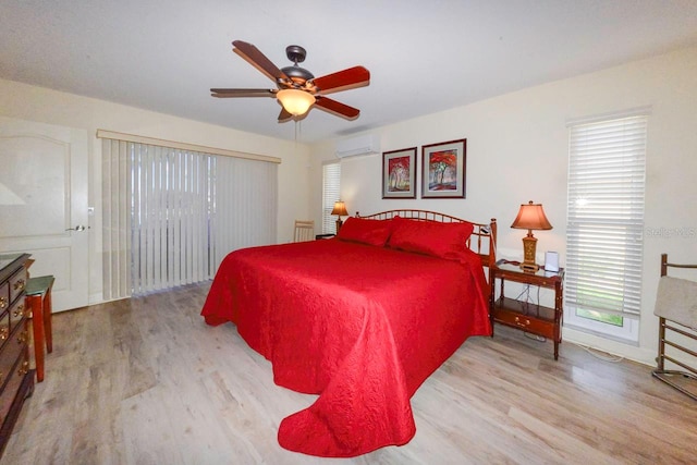 bedroom featuring multiple windows, a wall mounted AC, ceiling fan, and light hardwood / wood-style floors