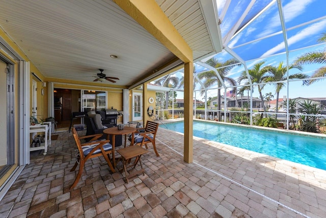 view of swimming pool featuring ceiling fan, glass enclosure, and a patio