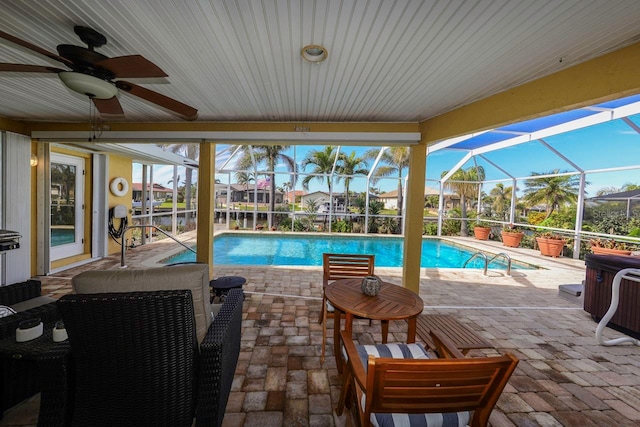 view of swimming pool with ceiling fan, a lanai, and a patio area