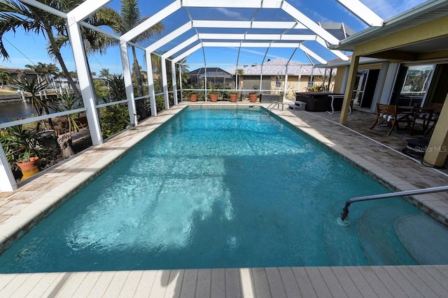 view of pool featuring a lanai, a patio area, and a water view