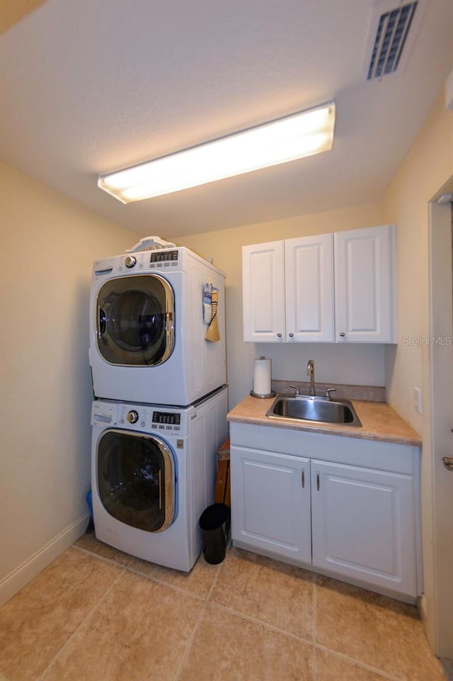 washroom with cabinets, stacked washer / drying machine, sink, and light tile patterned floors