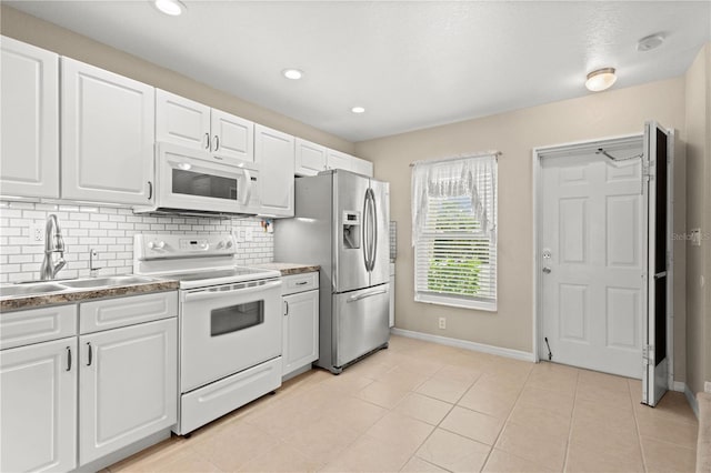 kitchen with white appliances, light tile patterned floors, decorative backsplash, white cabinets, and sink