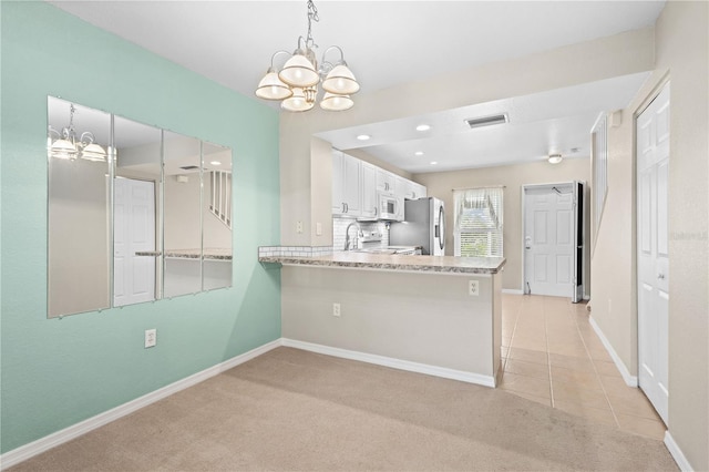 kitchen featuring kitchen peninsula, an inviting chandelier, white cabinetry, and pendant lighting