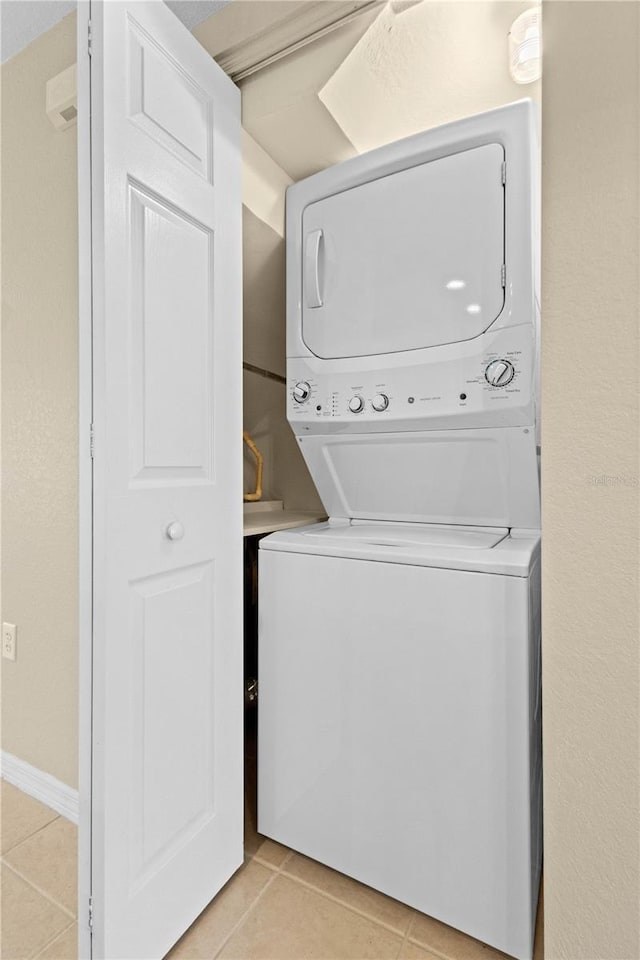 clothes washing area featuring stacked washing maching and dryer and light tile patterned floors