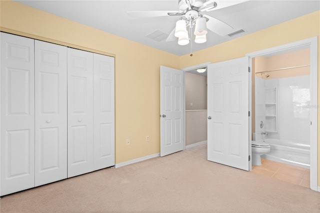 unfurnished bedroom featuring light colored carpet, ensuite bathroom, a closet, and ceiling fan