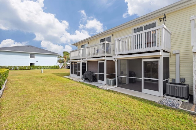 back of house featuring a sunroom, a lawn, and central AC