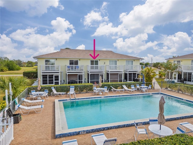 rear view of property with a community pool and a patio