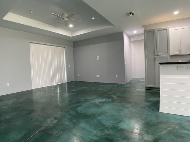 unfurnished living room with a tray ceiling and ceiling fan