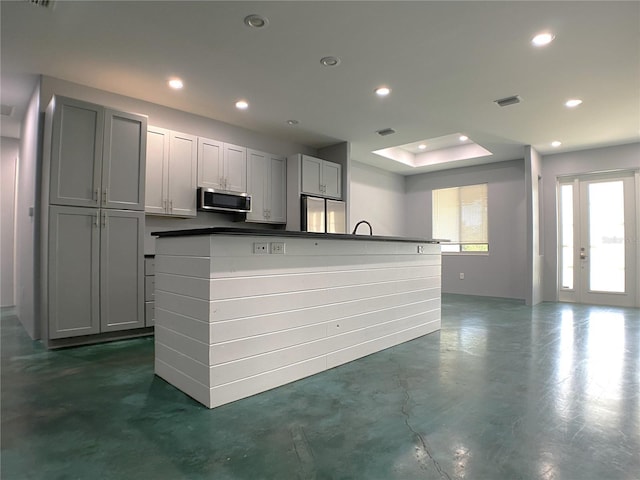 kitchen with stainless steel appliances, an island with sink, gray cabinets, and french doors