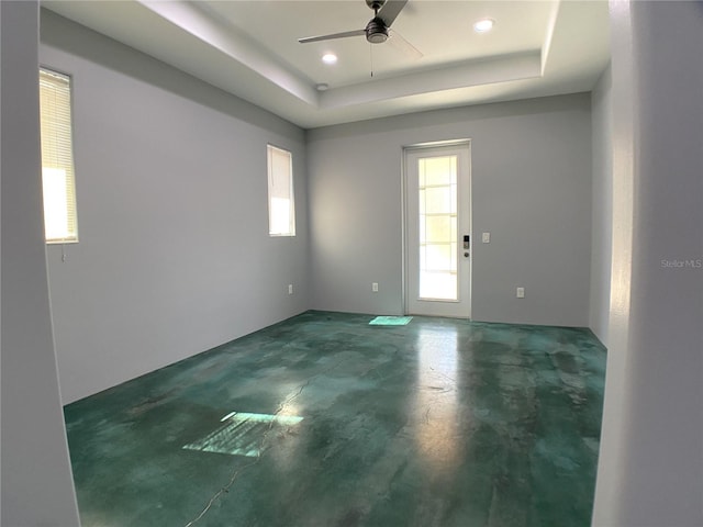 empty room with a raised ceiling and ceiling fan