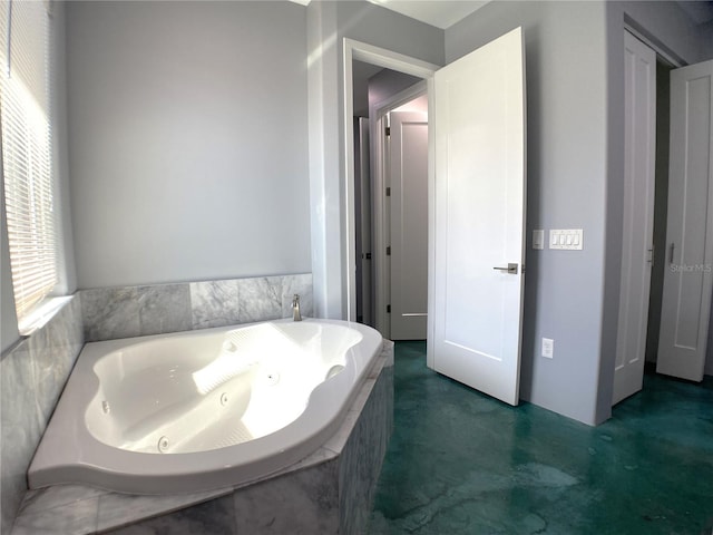 bathroom with concrete floors and tiled bath