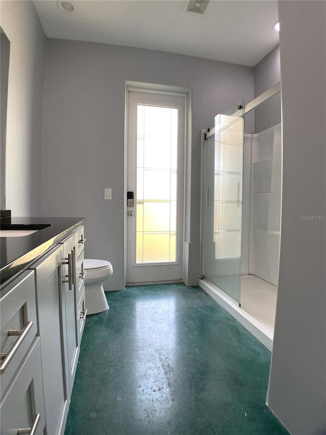 bathroom featuring vanity, a shower with shower door, concrete flooring, and toilet