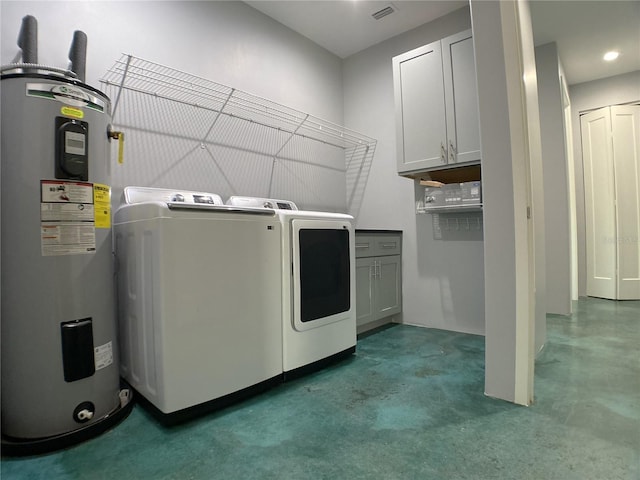 clothes washing area featuring cabinets, washing machine and dryer, and water heater