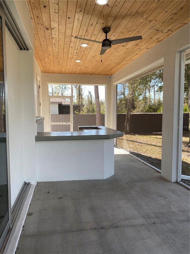 unfurnished sunroom with wooden ceiling and ceiling fan