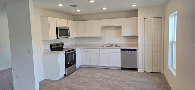 kitchen with plenty of natural light, sink, white cabinetry, and stainless steel appliances