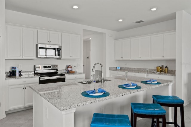 kitchen featuring a kitchen breakfast bar, stainless steel appliances, white cabinets, and an island with sink