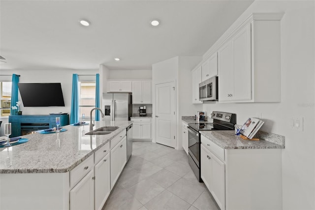 kitchen featuring sink, white cabinetry, a kitchen island with sink, light stone countertops, and stainless steel appliances