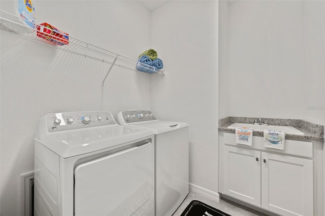 clothes washing area with washer and dryer, cabinets, and sink