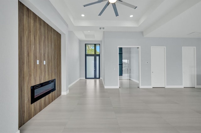 living room featuring ceiling fan, a fireplace, wooden walls, and a raised ceiling