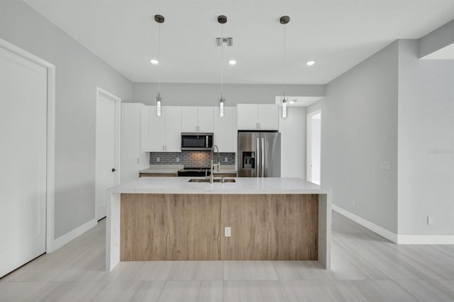 kitchen with white cabinetry, an island with sink, appliances with stainless steel finishes, decorative light fixtures, and sink