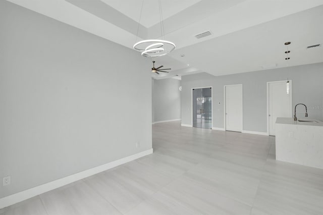 unfurnished living room with sink and ceiling fan with notable chandelier