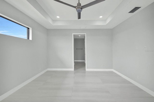 spare room with ceiling fan and a raised ceiling