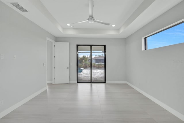 spare room featuring ceiling fan and a raised ceiling