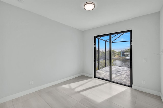 unfurnished room featuring a water view and light tile patterned floors