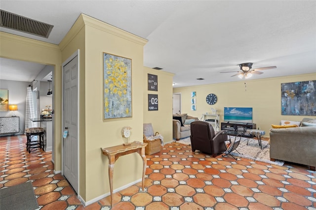 tiled living room with ceiling fan and crown molding