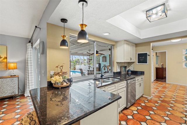 kitchen featuring dark stone countertops, tasteful backsplash, sink, hanging light fixtures, and ceiling fan