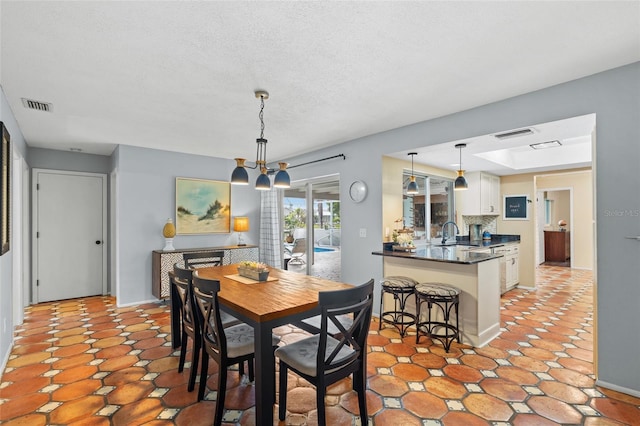 dining room featuring a textured ceiling, an inviting chandelier, and sink