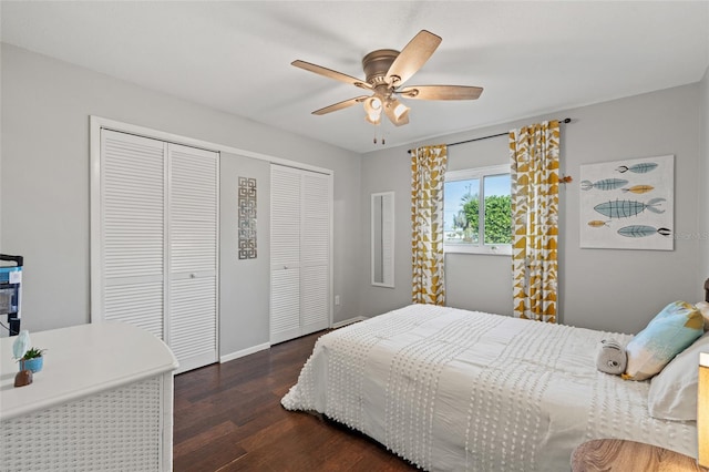 bedroom featuring ceiling fan, dark hardwood / wood-style flooring, and two closets