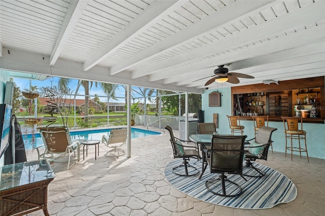 view of patio featuring ceiling fan, a bar, and glass enclosure