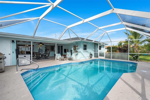 view of pool with ceiling fan, a patio, and glass enclosure