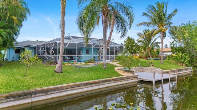 rear view of property featuring a lanai, a lawn, and a water view