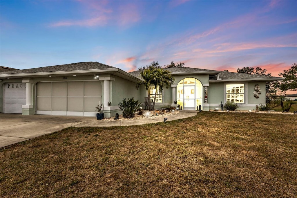 ranch-style home featuring a garage and a lawn