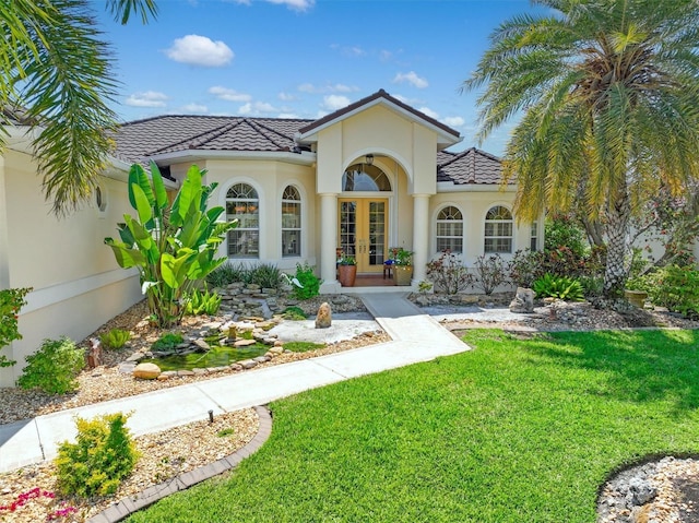 mediterranean / spanish home with a front lawn and french doors