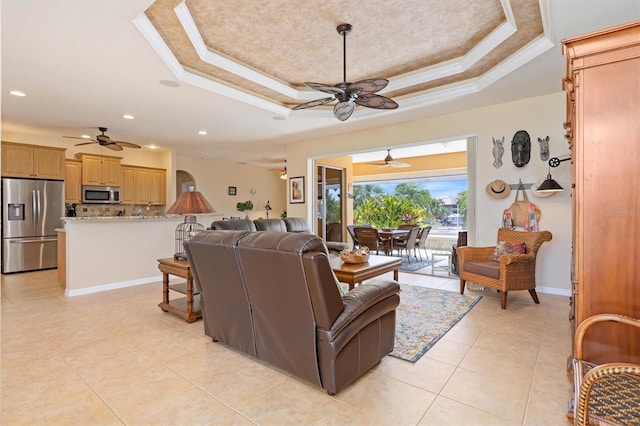 living room with light tile patterned flooring, crown molding, and a tray ceiling