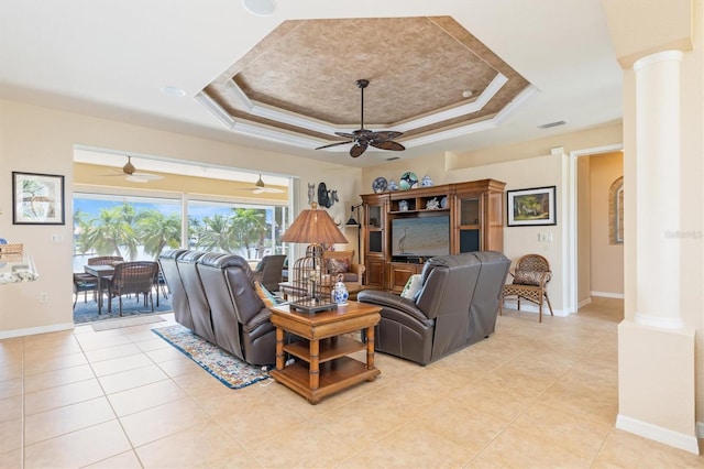 tiled living room featuring ceiling fan, a tray ceiling, and ornate columns