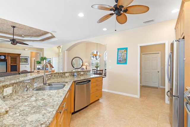 kitchen featuring light stone countertops, appliances with stainless steel finishes, sink, a raised ceiling, and crown molding