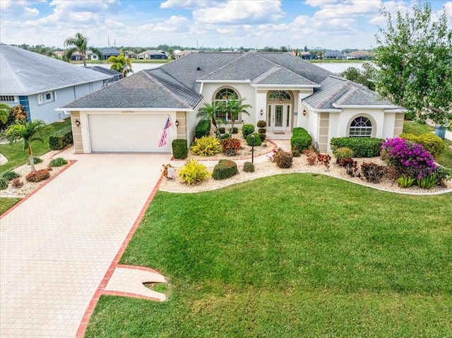 view of front of house with a garage, a front lawn, and a water view