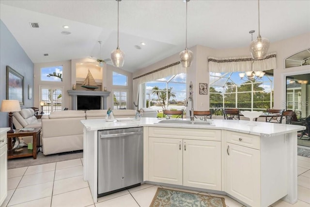 kitchen with stainless steel dishwasher, light tile patterned floors, sink, and pendant lighting