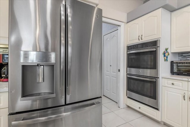 kitchen featuring light tile patterned floors, appliances with stainless steel finishes, and white cabinetry