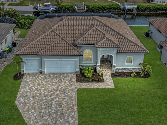 view of front of home with a garage, a water view, a front yard, and central AC unit