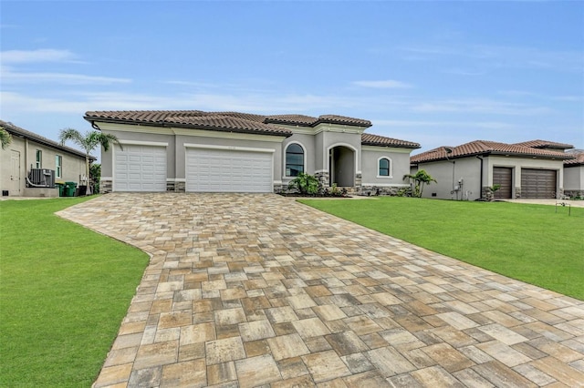 mediterranean / spanish-style home featuring cooling unit, a garage, and a front yard