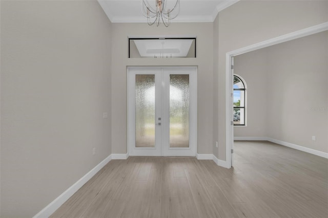 entryway with an inviting chandelier, ornamental molding, french doors, and light wood-type flooring