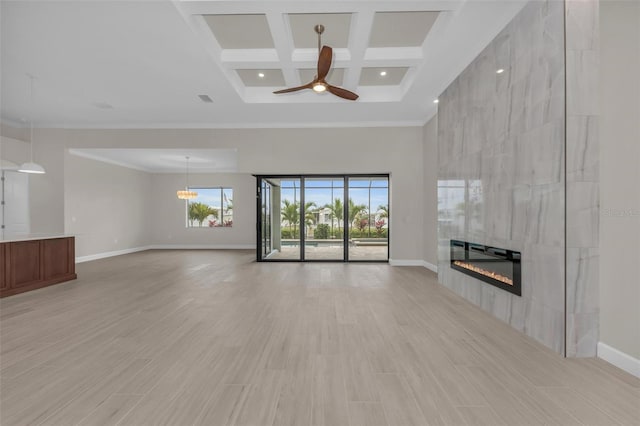 unfurnished living room featuring coffered ceiling, crown molding, ceiling fan, beam ceiling, and a tiled fireplace